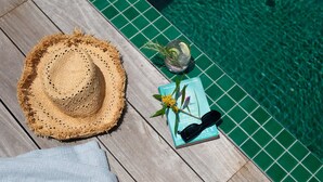 A wooden deck with a straw hat, a book, sunglasses, and a drink with a garnish. - Three One Bedroom Cabins (Bangalow)