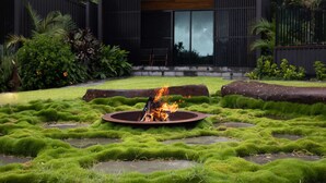 A modern outdoor area with a fire pit surrounded by lush green moss. - Balaka Exclusive Property (Bangalow)