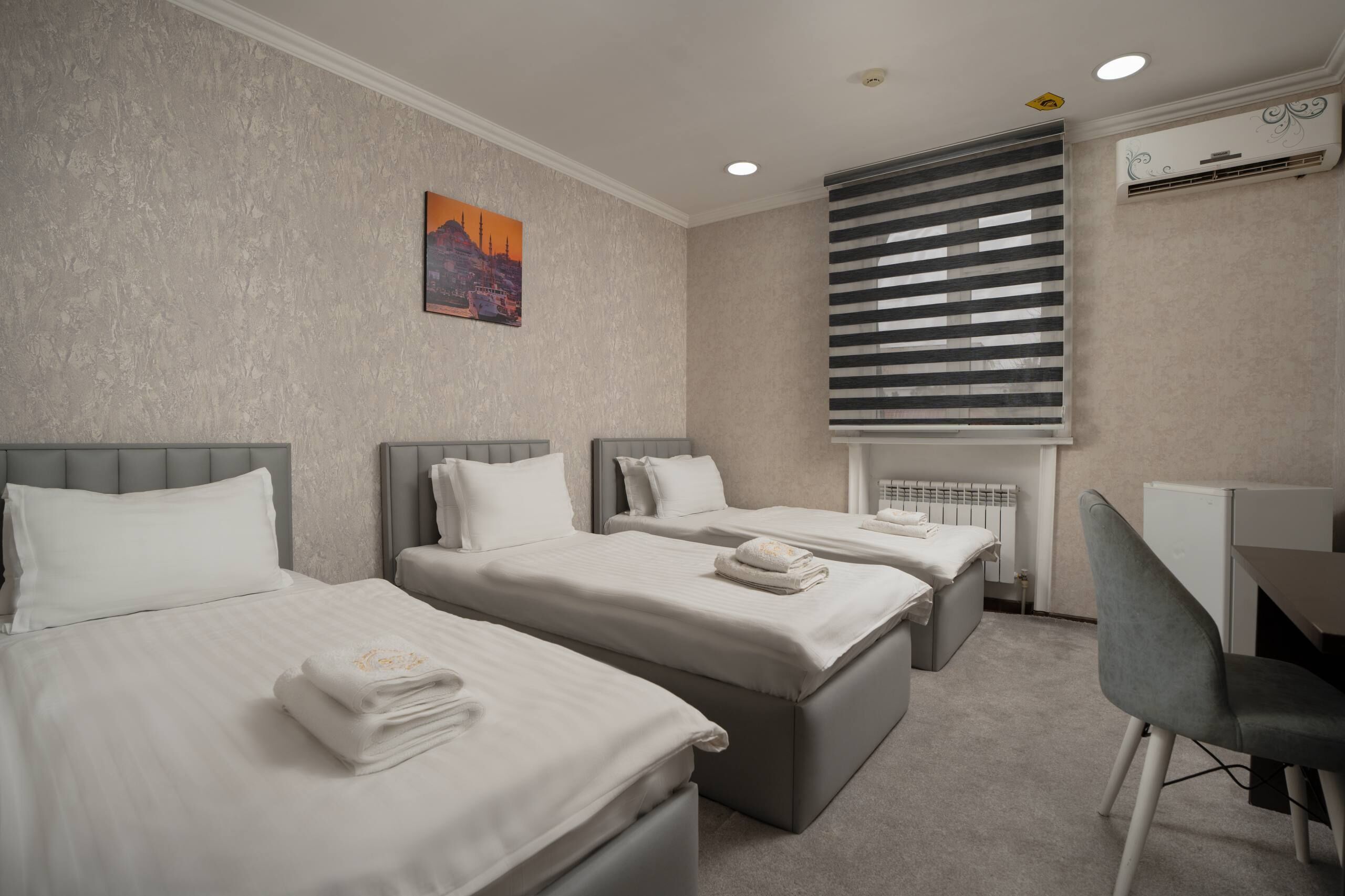 Habitación de hotel con tres camas, un escritorio y una silla.