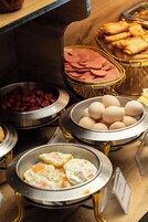 A buffet with various food items including eggs, ham, and sausages.