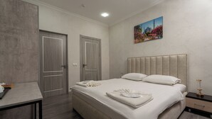 A hotel room with a large bed, a desk, and two doors. - SV Stable Visitor Hotel (Tashkent)
