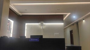 A reception area with a reception desk, a wall-mounted fan, and a sign labeled "RECEPTION". - Hotel Ramsons International  (Hunsur)