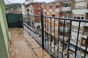 Un edificio de varios pisos con balcones, una entrada con reja y piso de baldosas.