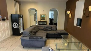 Un salon moderne avec un canapé d’angle, une table basse en verre et un meuble de rangement noir pour les appareils électroniques.