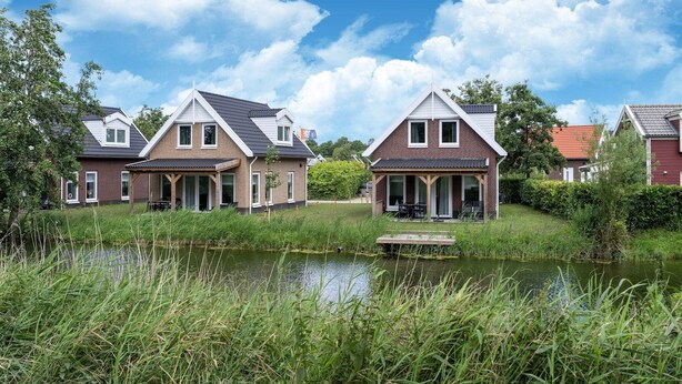 A row of houses with a pond in the foreground. - Holiday Home by Lake Beach Simonshaven (Simonshaven)
