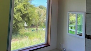 Ein Badezimmer mit großem Fenster, Waschbecken und Spiegel.