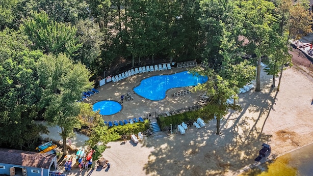 An aerial view of a resort with multiple swimming pools, lounge chairs, and a building with a flag.