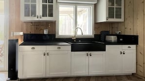 Een keuken met witte kasten, een zwart aanrecht, een raam en een spoelbak.