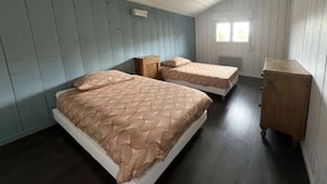 A room with two beds, wooden cabinets, and a window. - Villa with pool near the lake (CAZAUX)