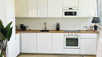 A modern kitchen with white cabinets, a marble countertop, and a dining area with a table and chairs.