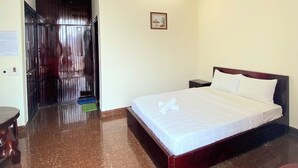 Habitación de hotel con una cama grande, una lámpara de techo, un equipo de aire acondicionado y una puerta de madera.