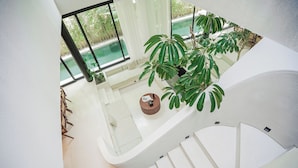 A modern interior with a staircase, a seating area, and a view of an outdoor swimming pool. - Suave Villa Canggu (Canggu)