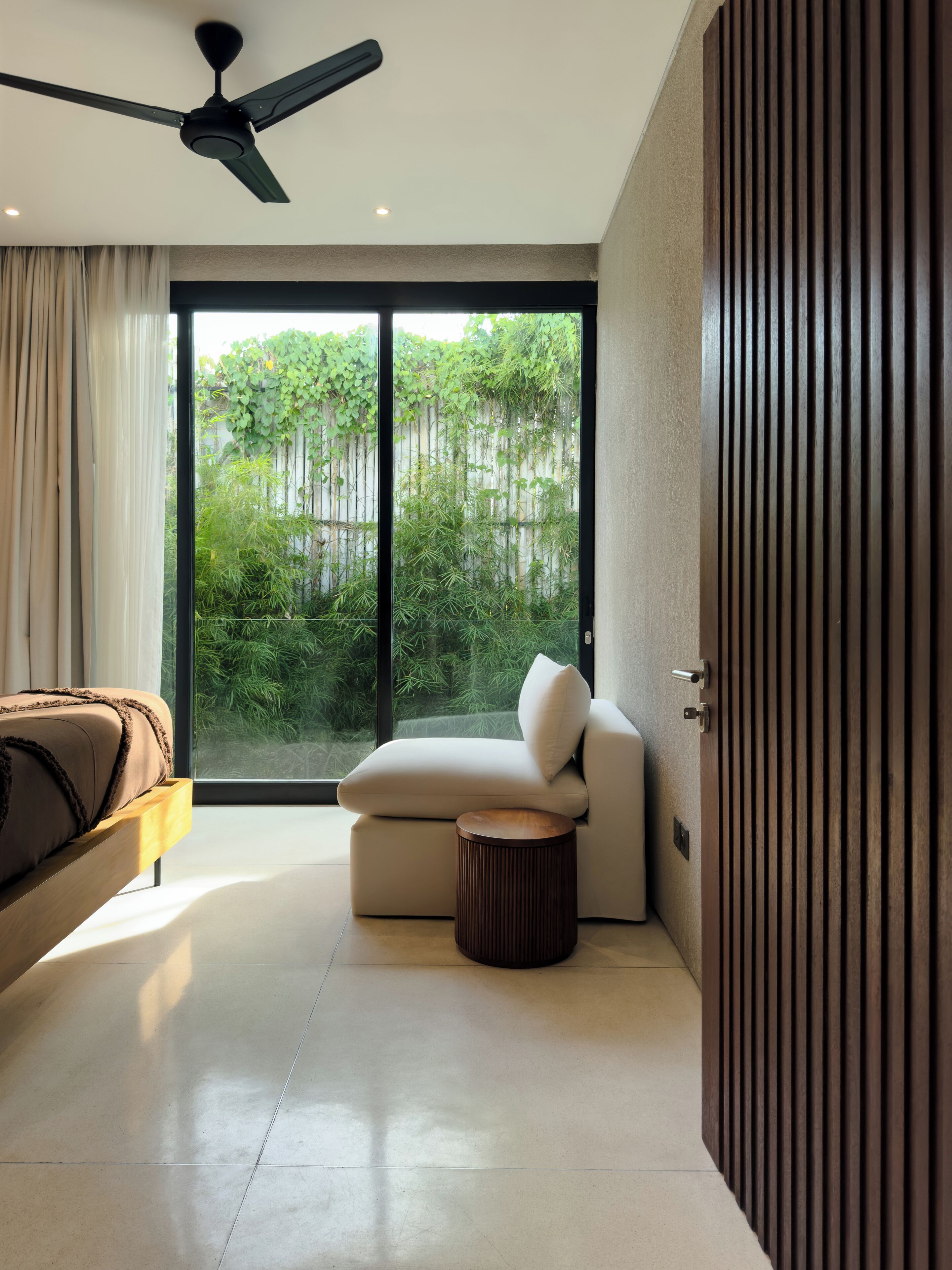 Un dormitorio moderno con un sofá, una mesita redonda de madera y un ventilador de techo.
