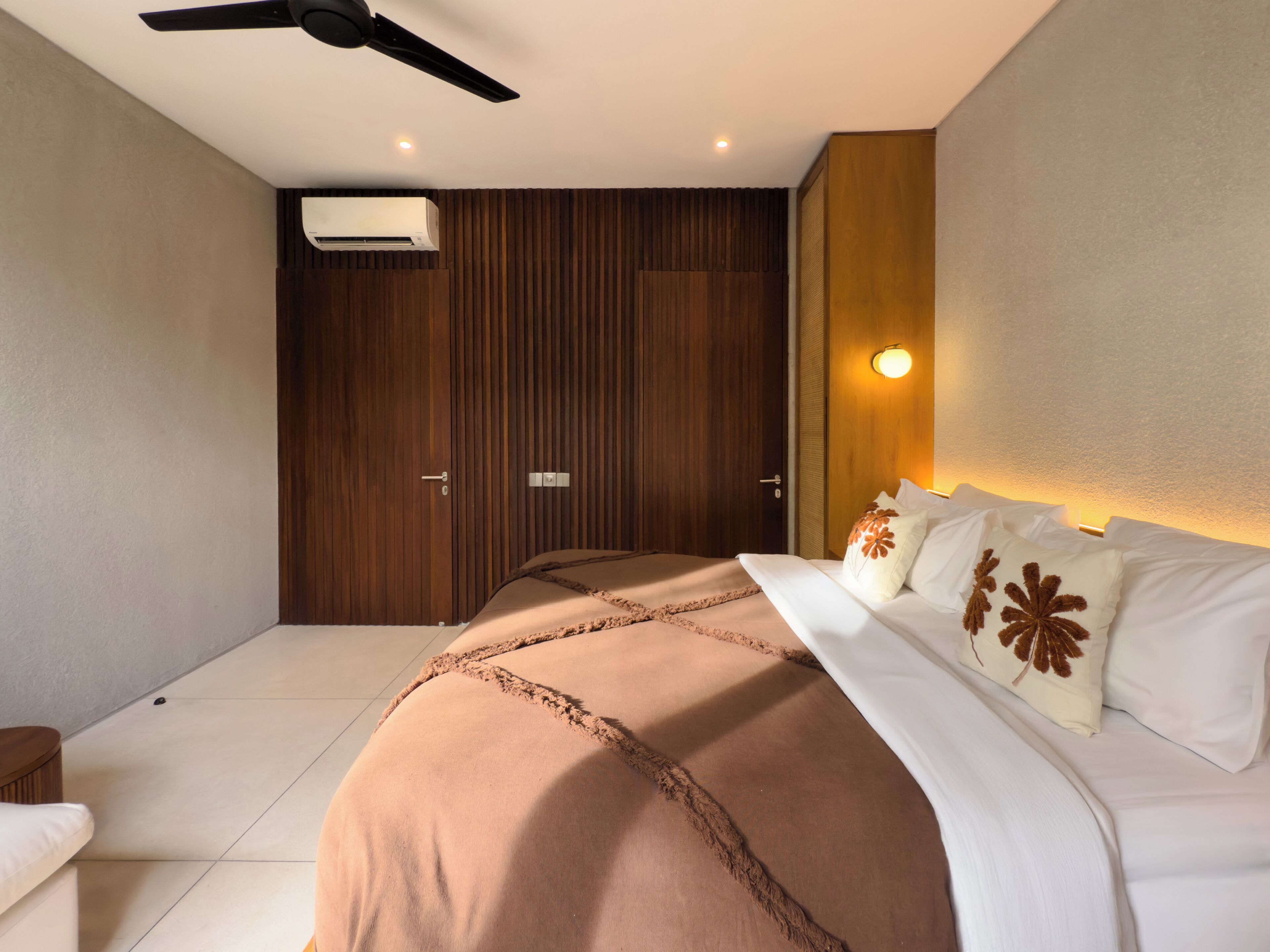 A modern bedroom with a large bed, a ceiling fan, and a wall-mounted air conditioner.