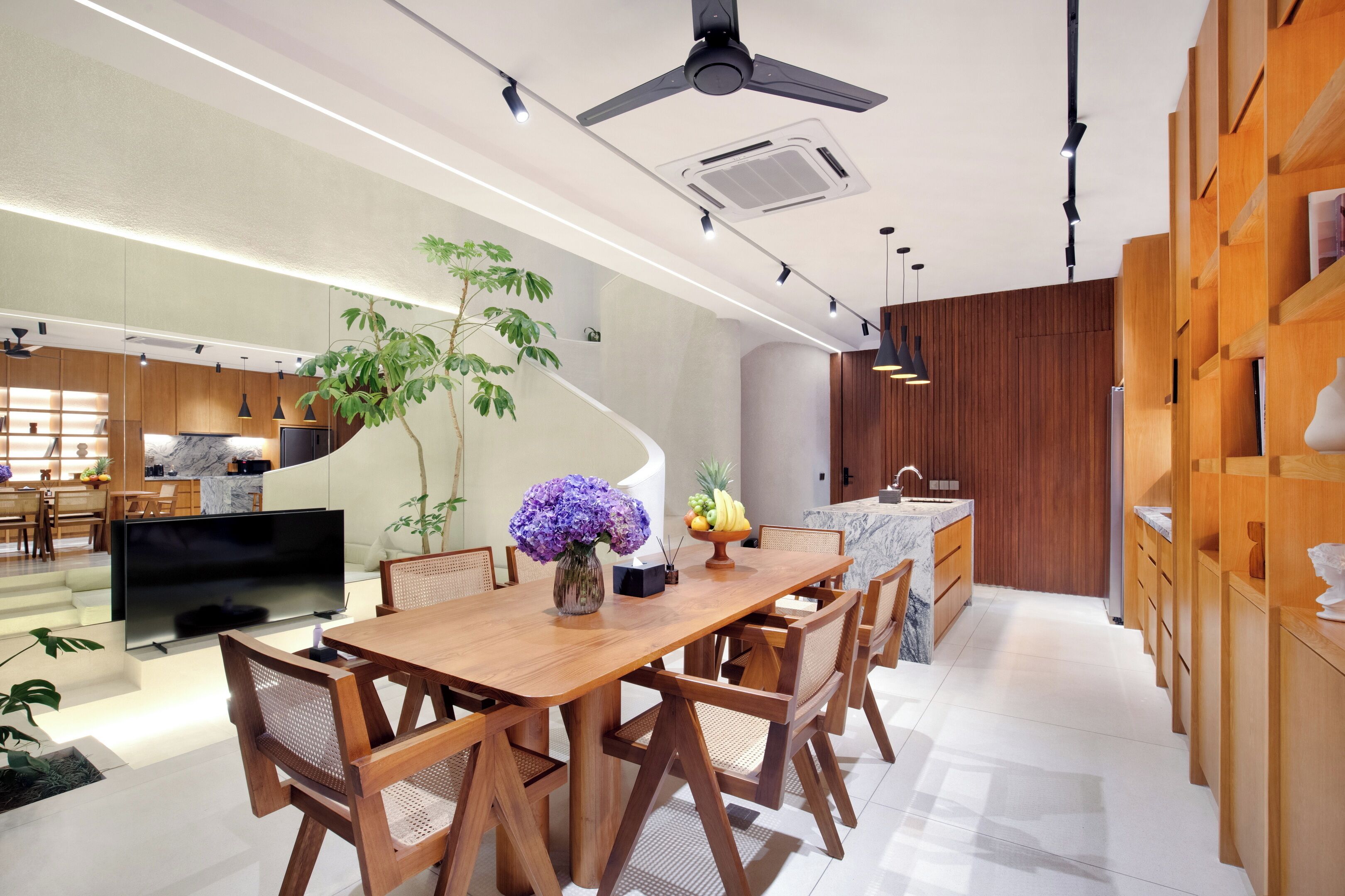 A modern kitchen with wooden cabinets, a marble countertop, and a dining area with a wooden table and chairs.