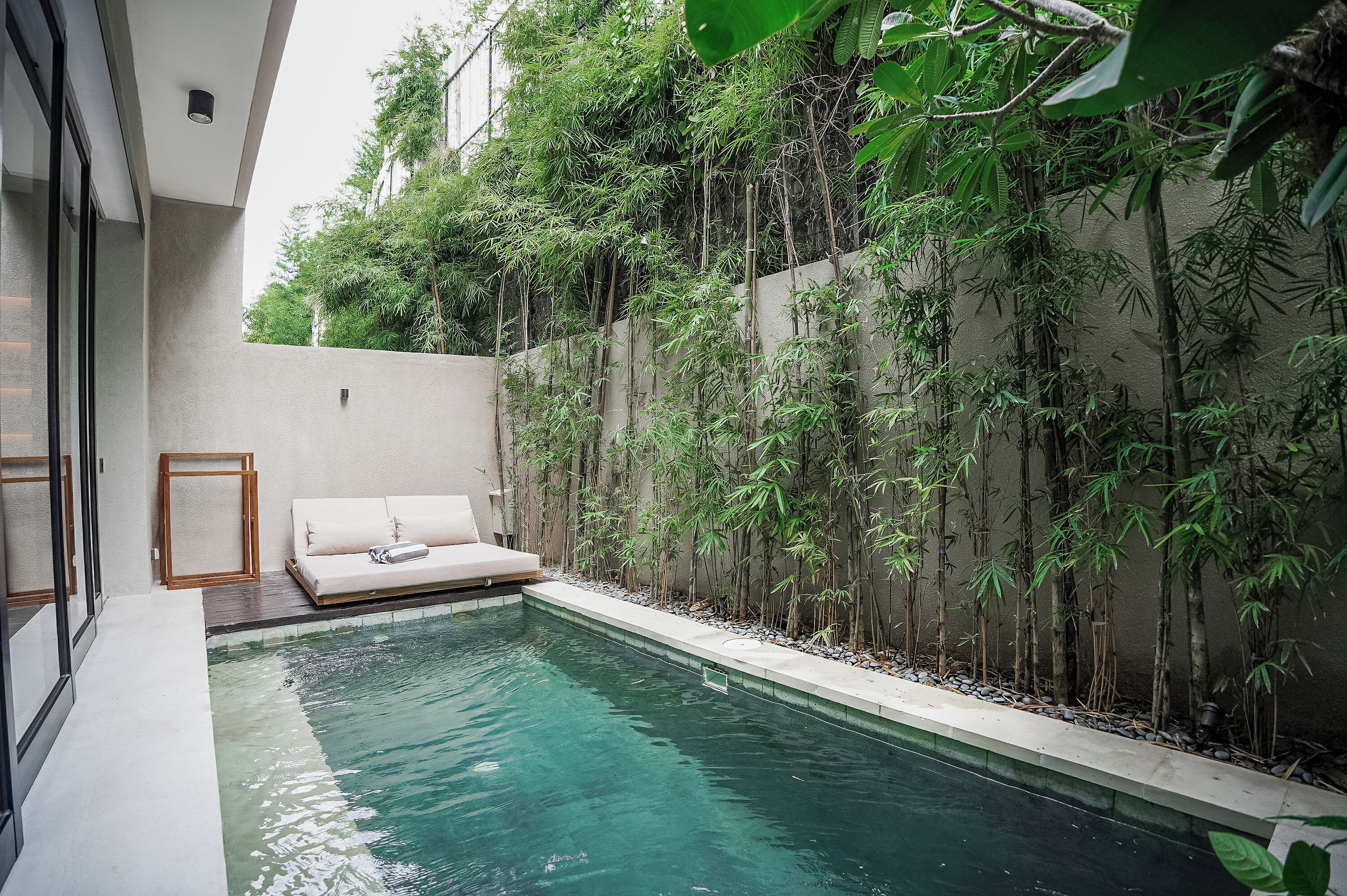A modern pool area with a built-in bench and a bamboo wall.