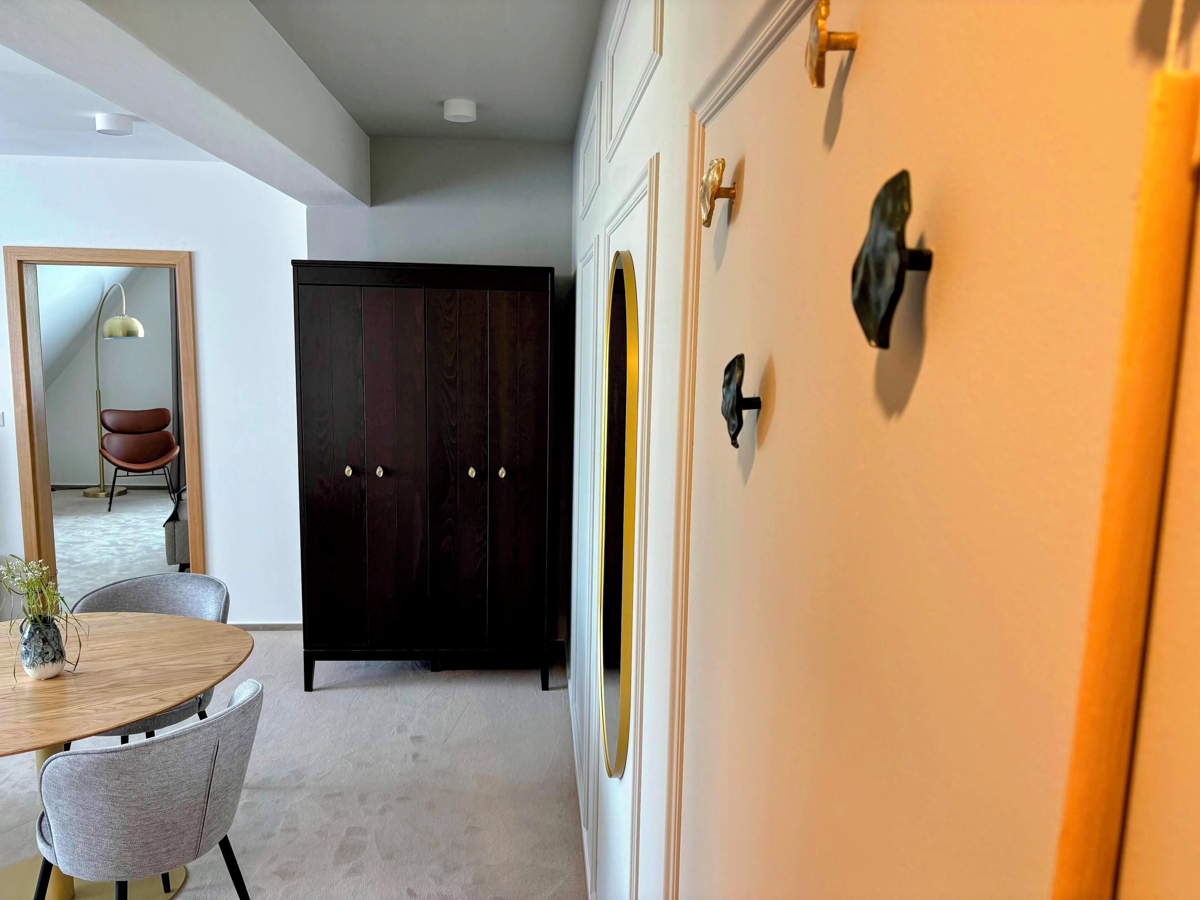 Un intérieur moderne comprenant un coin repas, une armoire en bois foncé et une porte blanche dotée d’une poignée dorée.
