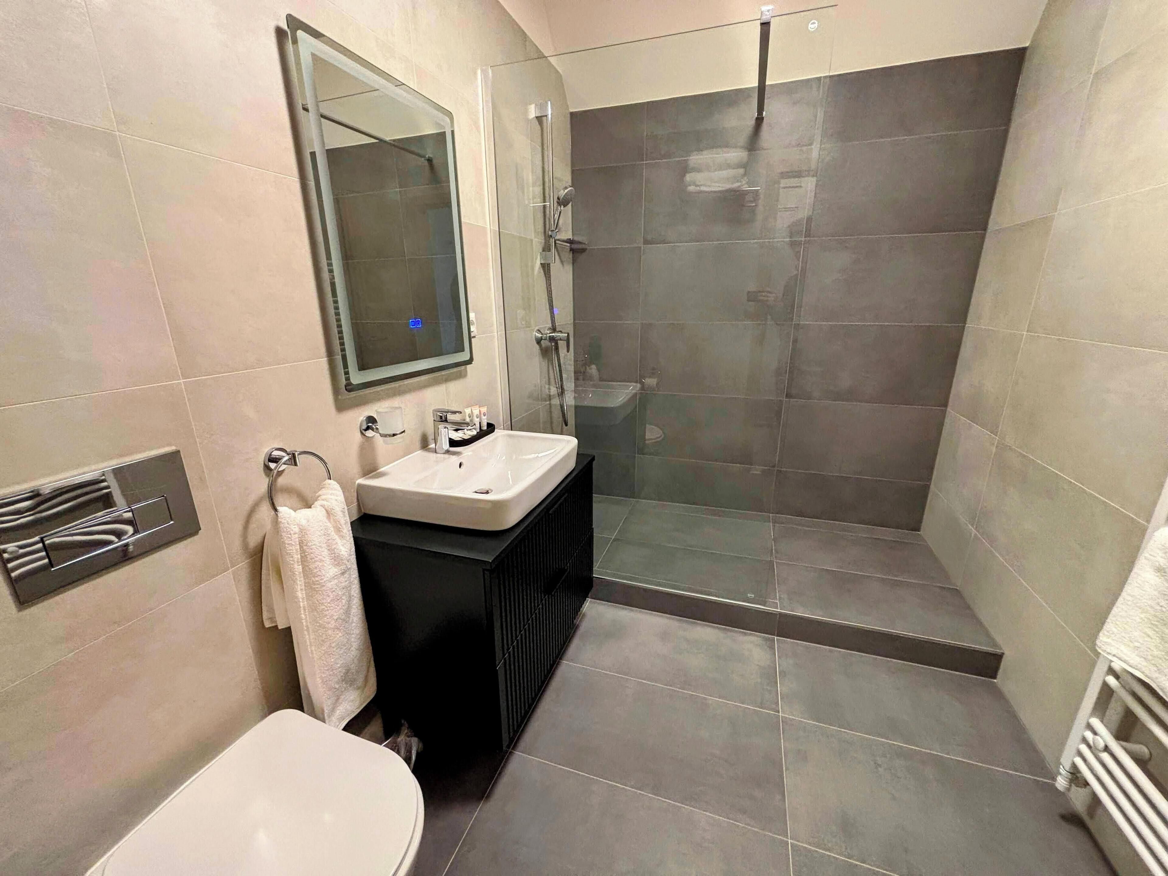 Une salle de bain moderne avec une douche à parois de verre, un lavabo blanc et des toilettes.