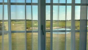 Une vue à travers une fenêtre donnant sur un terrain de golf et un étang.