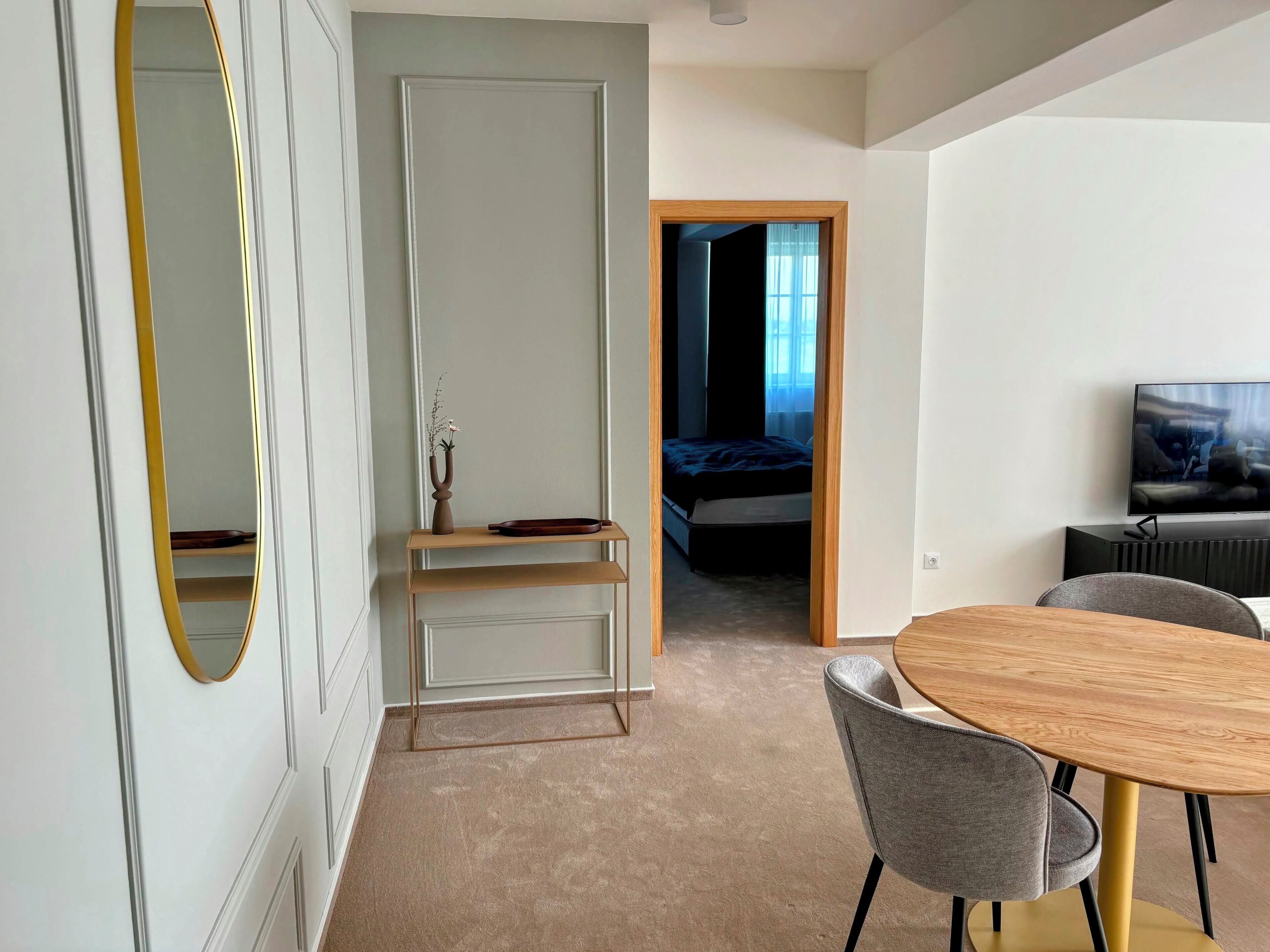 A modern bedroom with a bed, a TV, a desk, and a chair.