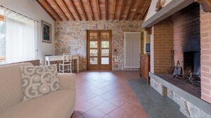 A cozy room with a stone wall, a fireplace, a wooden ceiling, and a tiled floor. - Casolare Torre With Pool And Ac (Poggibonsi)