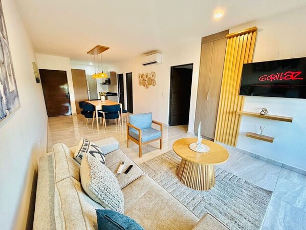 Un salon moderne avec un canapé, une table basse et un téléviseur fixé au mur.