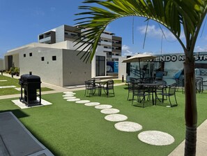 Une terrasse extérieure avec un revêtement de gazon synthétique, un barbecue et des meubles d’extérieur.