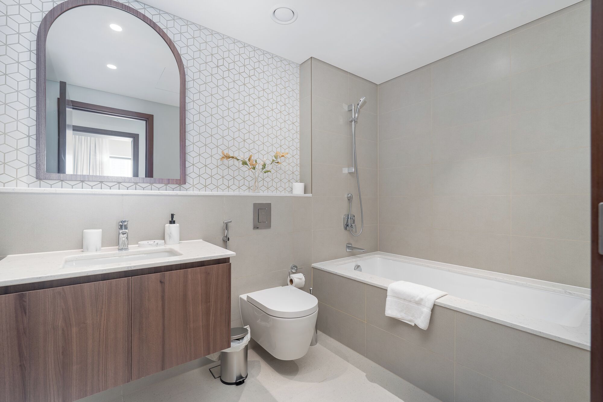 A modern bathroom with a vanity, toilet, and bathtub.