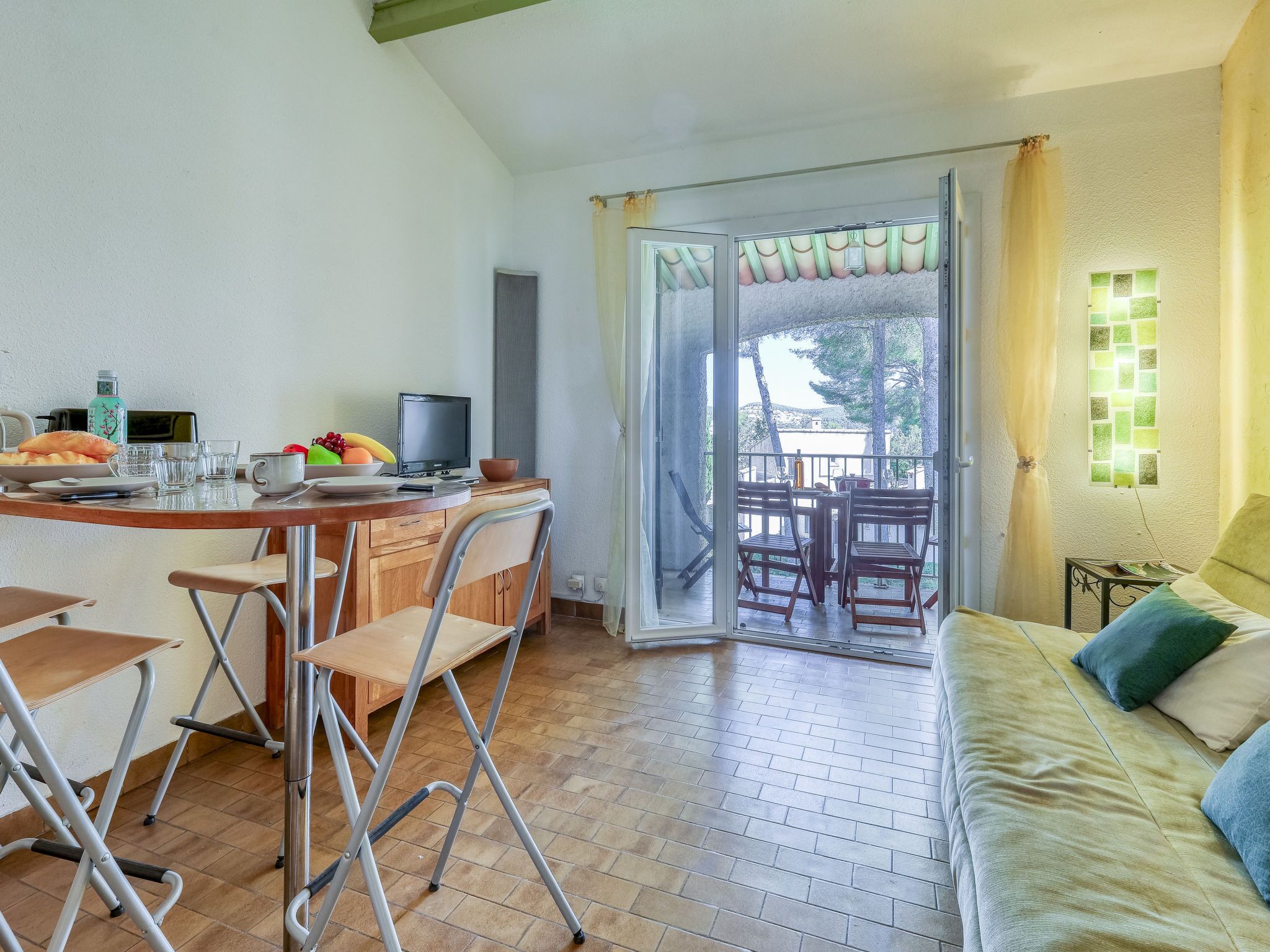 A cozy room with a dining area, a sofa, and a balcony with a view.