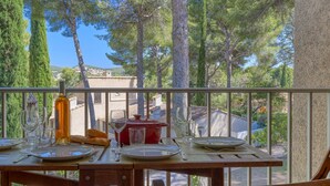 A dining table set outdoors with a bottle of wine, glasses, and bread. - Les Hauts du Port by Interhome (Saint Cyr sur mer Les Lecques)
