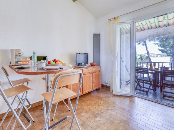 Een compacte keuken met een eethoek, een televisie en een balkon met uitzicht.