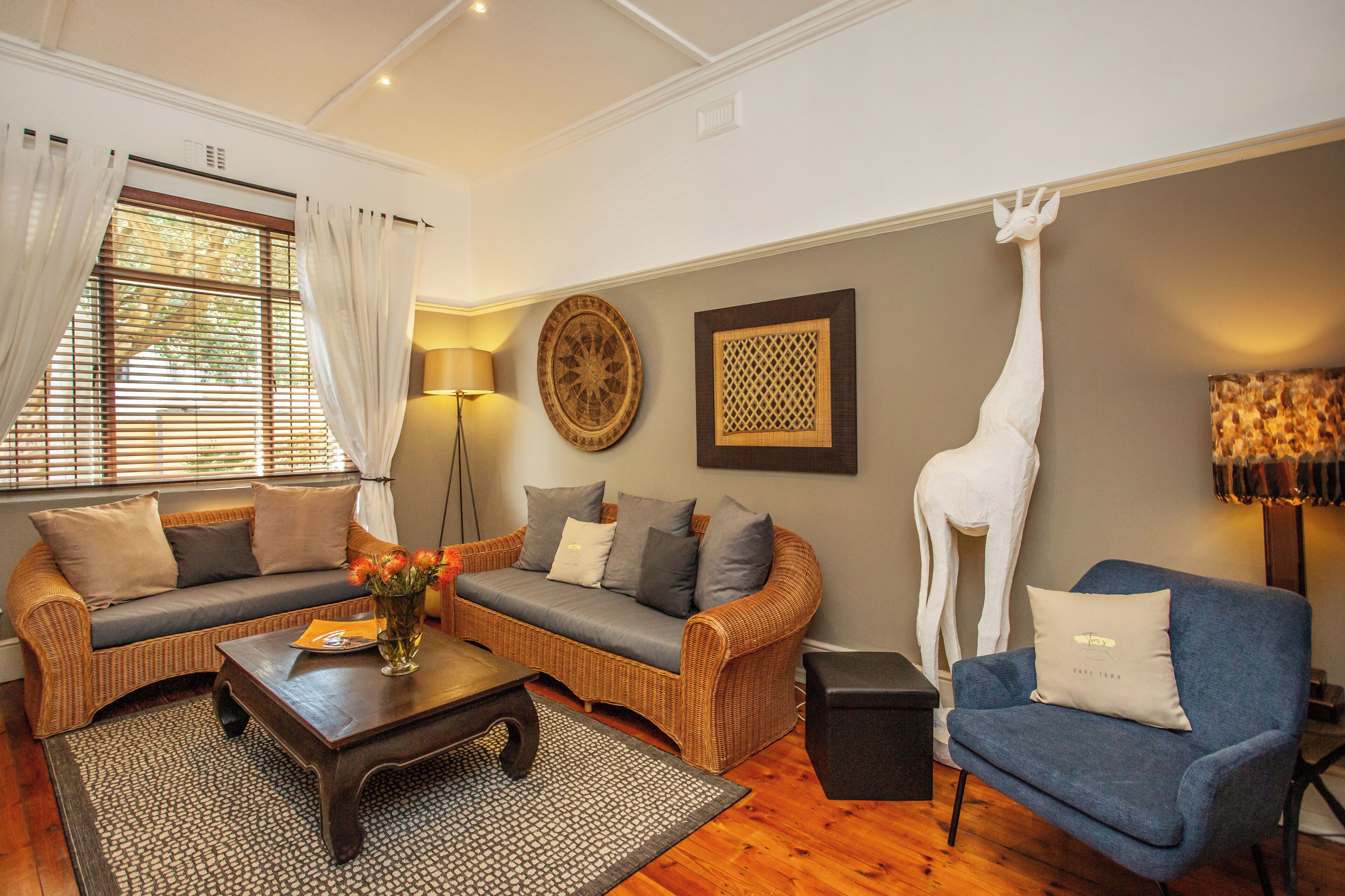 Ein Wohnzimmer mit Sofa, Sessel, Couchtisch und dekorativen Elementen, darunter eine Giraffenskulptur.