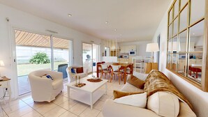A spacious living room with a large window, a dining area, and a kitchen.