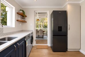 A modern kitchen with a built-in dishwasher, a refrigerator, and a window with a view of trees.