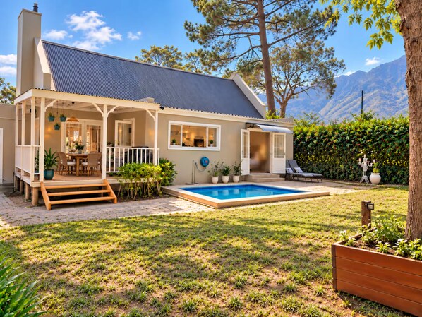 A house with a swimming pool, a covered patio, and a view of mountains.