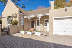 A residential property with a covered patio, a garage, and a brick driveway.