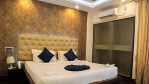 A hotel room with a large bed, a headboard, a bedside table with a lamp, and a sliding glass door. - Mystic Apartotel Hebbal (Bengaluru)