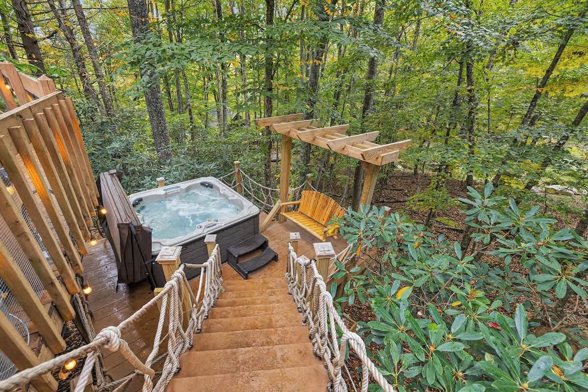 A hot tub surrounded by wooden railings and a wooden deck, set in a forested area.