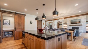A spacious kitchen with a large island, wooden cabinets, and pendant lighting.