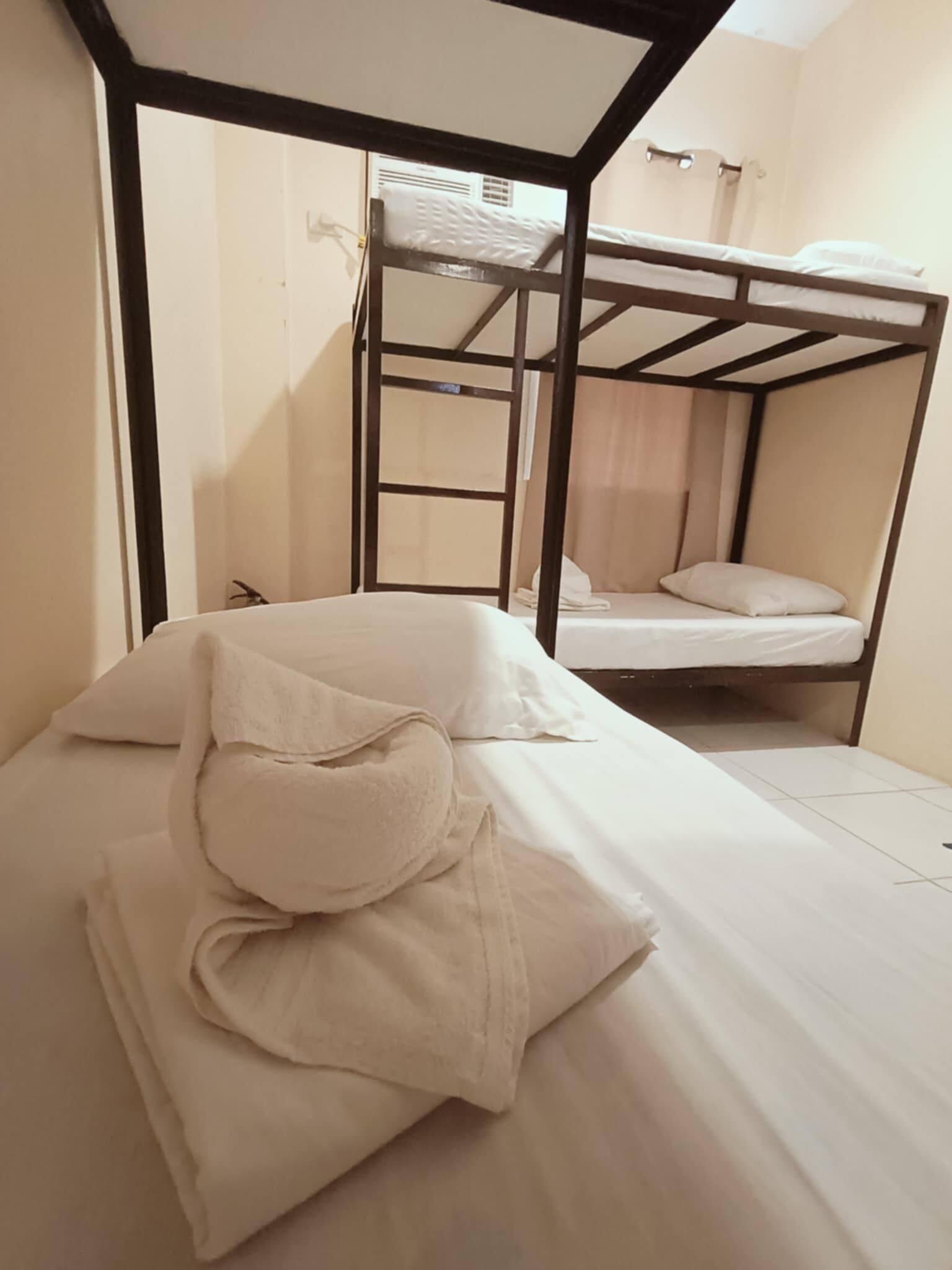 A bunk bed room with a wooden frame, a white mattress, and a white blanket.