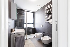 A modern bathroom with a glass shower enclosure, a toilet, a bidet, and a sink. - East Uptown P Pasolini 74 Cascina Merlata (Milan)