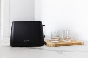 A black portable water purifier on a wooden tray with two glasses. - East Uptown P Pasolini 74 Cascina Merlata (Milan)
