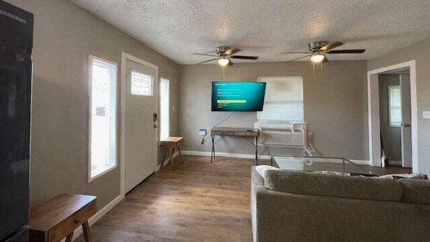 Un salon doté d’un téléviseur à écran plat fixé au mur, d’un ventilateur de plafond et d’un banc en bois.