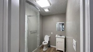 Une salle de bain avec douche, toilettes et lavabo.