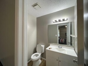 A bathroom with a toilet, sink, and mirror. - Cozy 1-Bed, 1-Bath with Full Kitchen Near Fort Sill (Lawton)