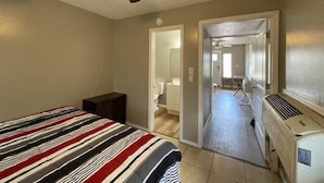 Une chambre à coucher avec un lit, un ventilateur de plafond et un couloir menant à une salle de bain.