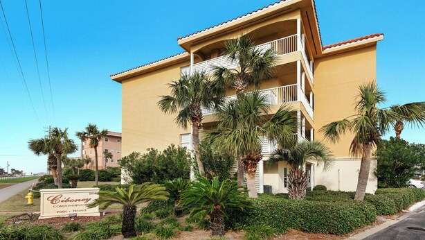 A multi-story building with balconies, surrounded by palm trees and a sign indicating it is a condominium complex. - Ciboney 3013 (Miramar Beach)