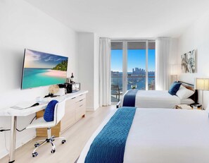 Una habitación de hotel moderna con una cama grande, un escritorio, un televisor de pantalla plana y un balcón con vistas a la ciudad.