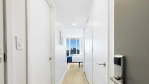 A narrow hallway leading to a bedroom with a city view, white walls, and a door with a handle. - Miami Studio, Amazing Amenities, Infinite View (Hallandale Beach)