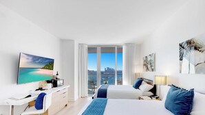 Habitació d'hotel moderna amb un llit gran, una taula de treball, una cadira i vistes a la ciutat.